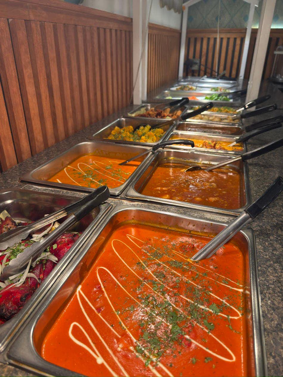 A long Indian buffet line with chafing dishes ready for guests